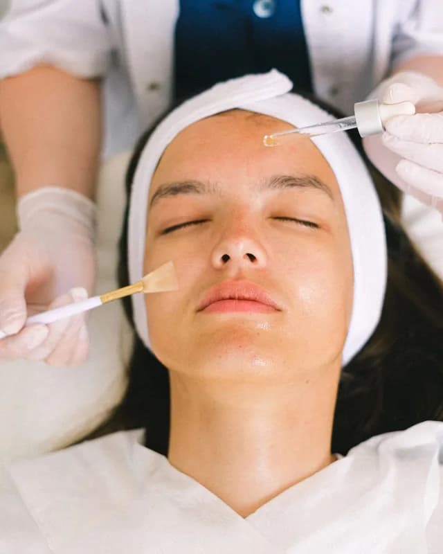 Cena ilustrativa de cuidado facial profissional com aplicação de cosmético, sem agulhas.